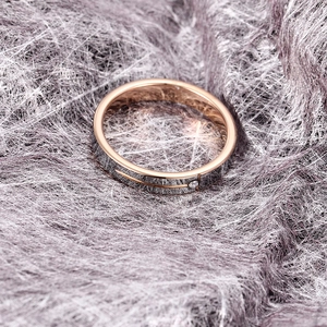 Polished silver tungsten ring with rose gold interior and diamond inlay on textured background