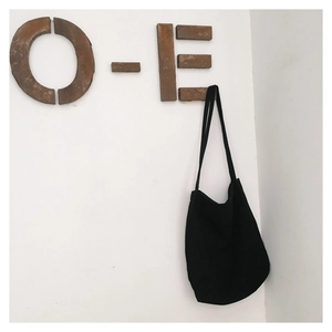 Detail of minimalist black canvas tote bag hanging on a hook for daily commute