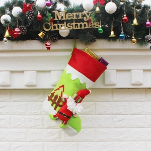 Green and red Christmas stocking with Santa and tree hanging on a decorated mantel