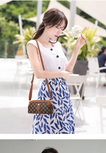 Outdoor shot of a brown checkered crossbody bag with adjustable strap and double zippers