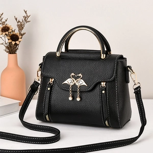 Black lychee leather handbag with swan heart clasp and pearl pendant accessory