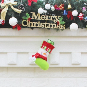 Green and red Christmas stocking with snowman decor hanging on festive mantelpiece