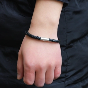 Minimalist black braided leather bracelet with silver magnetic clasp on a wrist