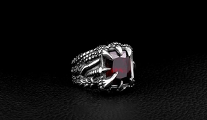 Detail of vintage dragon claw ring with large rectangular red gemstone on leather background