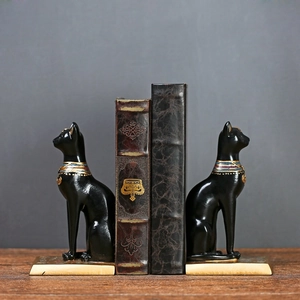 Paar Egyptische Bastet kattenboekensteunen van hars met gouden voet op houten bureau