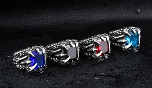 Macro shot of gothic dragon claw rings with vibrant zircon stones on a wet black surface