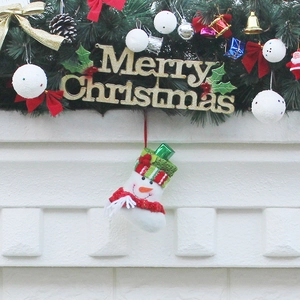 Christmas wreath with Merry Christmas sign and white snowman stocking on white brick wall