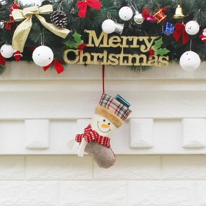 Plaid fabric Christmas stocking with snowman motif hanging on a decorated pine branch