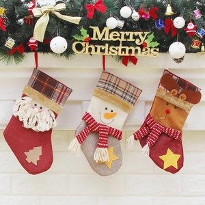 Trois chaussettes de Noël festives avec Père Noël, bonhomme de neige et renne au foyer