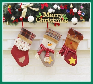 Trois chaussettes de Noël festives avec Père Noël, bonhomme de neige et renne sur la cheminée