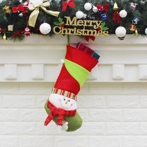 Knitted Christmas stocking with snowman pattern hanging on a decorated festive mantel