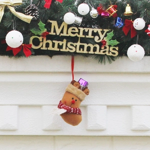 Chaussette de Noël marron avec écharpe rouge accrochée à une cheminée blanche décorée