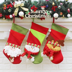Three festive Christmas stockings featuring Santa, snowman, and reindeer hanging on a mantel