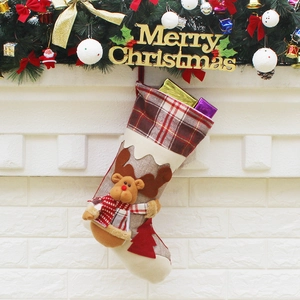 Christmas stocking with reindeer doll and red plaid hung on fireplace mantel decor