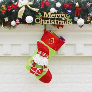 Knitted Christmas stocking with Santa Claus 3D doll hanging on a decorated fireplace