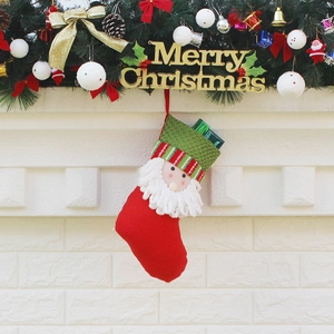 Red Santa Claus Christmas stocking with green knit cuff hanging on a festive fireplace