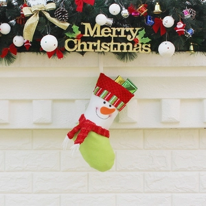 Christmas stocking with snowman design hanging on fireplace with festive greenery and ornaments