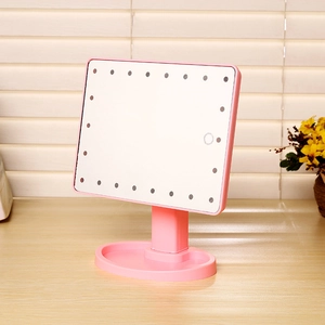 Pink LED makeup mirror with storage base and touch sensor on a wooden table