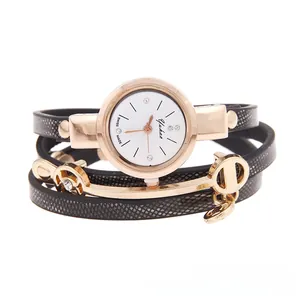 Detail of black leather wrap watch strap with gold studs and a metal D pendant