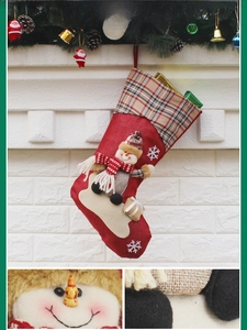 Detail of red Christmas stocking with snowman doll, plaid cuff and snowflake embroidery