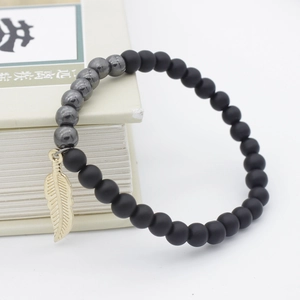 Black matte beaded bracelet with hematite accents and golden leaf charm on book edge