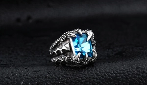 Macro detail of men's punk ring featuring blue gemstone and vintage silver dragon claws