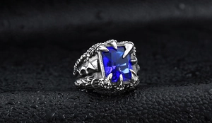 Detail of vintage dragon claw ring with blue rectangle gemstone on wet leather background