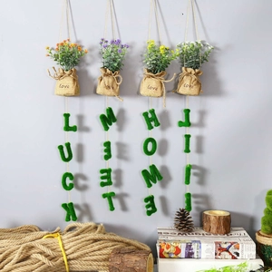 Detail of wall-mounted artificial plants in burlap bags with lucky moss letters