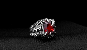 Macro shot of gothic dragon claw ring in vintage steel with large red zircon stone