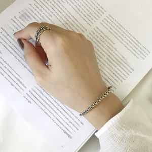 Macro shot of S925 sterling silver braided bracelet and ring on hands over book