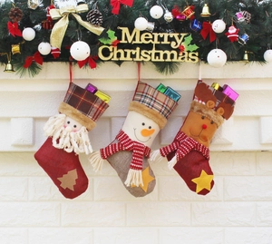 Trois chaussettes de Noël festives avec Père Noël, bonhomme de neige et renne sur mur de briques