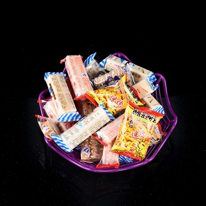 Close-up of Halloween purple spider candy basket filled with various snacks and cookies