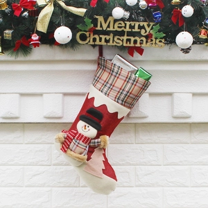 Christmas stocking with 3D snowman, red plaid cuff, hanging over a cozy fireplace