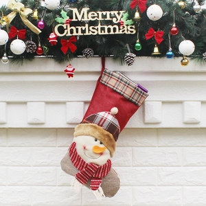 Red Christmas stocking with snowman decor and plaid patterns hanging on fireplace mantle