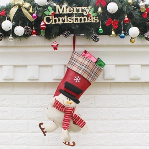 Chaussette de Noël avec bonhomme de neige suspendue à une cheminée décorée de fête