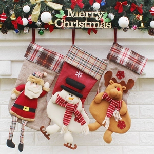 Trois chaussettes de Noël avec Père Noël, bonhomme de neige et renne sur mur de briques