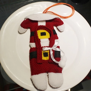 Christmas Santa suit cutlery holder set in red and white knit on a white ceramic plate