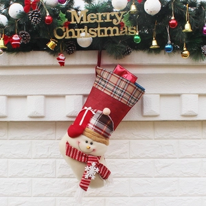 Christmas stocking with snowman pattern and plaid cuff hanging on festive fireplace decor