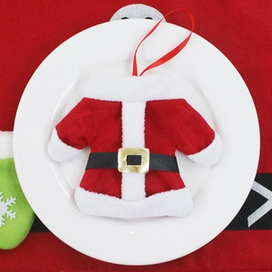 Miniature Santa suit cutlery holder on a white ceramic plate with red velvet background