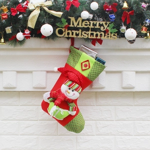 Knitted Christmas stocking with 3D snowman hanging on fireplace with festive decorations
