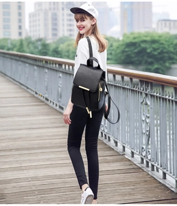 Urban lifestyle shot of a black faux leather drawstring backpack with gold metal zippers