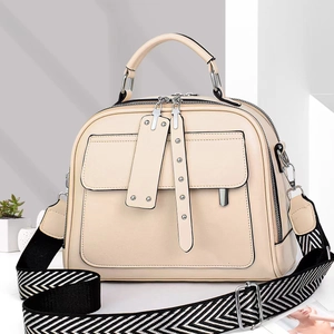 Detail van crème lederen crossbodytas met geweven riem en dubbele metalen ritsen