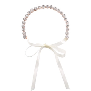 Detailed macro view of sparkling rhinestones on rose gold headband with white satin ribbon