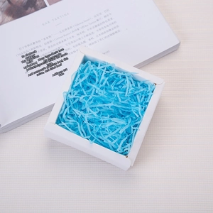 Sky blue shredded raffia paper filler inside a white square gift box on a stylish background