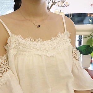 Detail of white lace off-the-shoulder top with intricate cotton linen floral embroidery