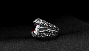 Close-up of retro dragon claw ring with red zircon on a black leather background