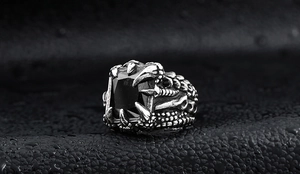 Detail of gothic dragon claw ring with large black rectangular gemstone on dark leather