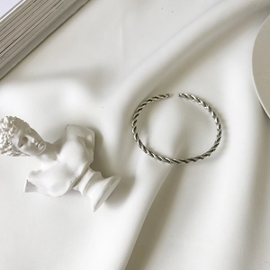 Detail of S925 sterling silver woven rope bracelet on white silk with plaster bust