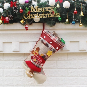 Christmas stocking with reindeer figure and plaid patterns hanging by the fireplace