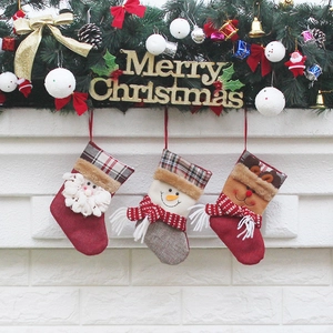 Three Christmas stockings with Santa, Snowman, and Reindeer designs on a festive fireplace